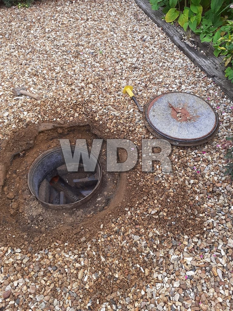 Manhole cover set in gravel drive