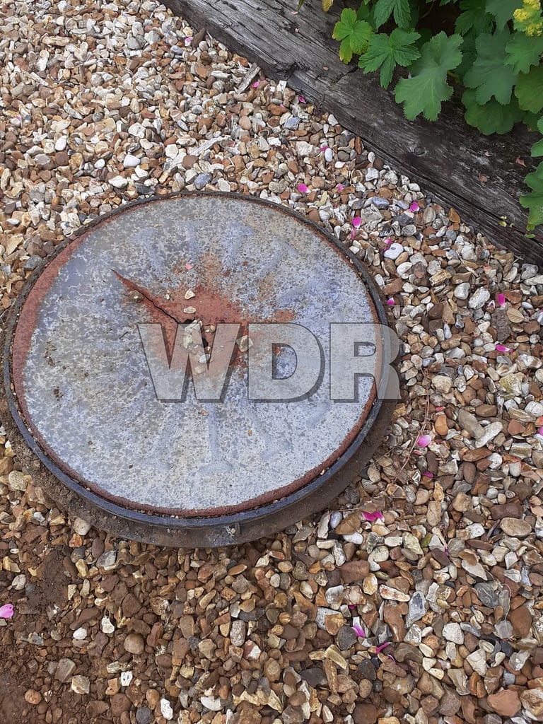 Manhole cover set in gravel drive